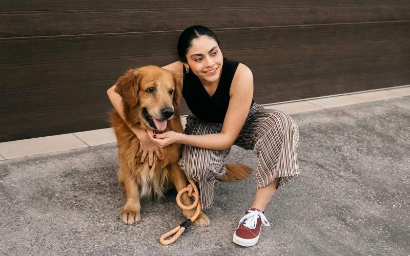 A woman kneeling next to a dog.